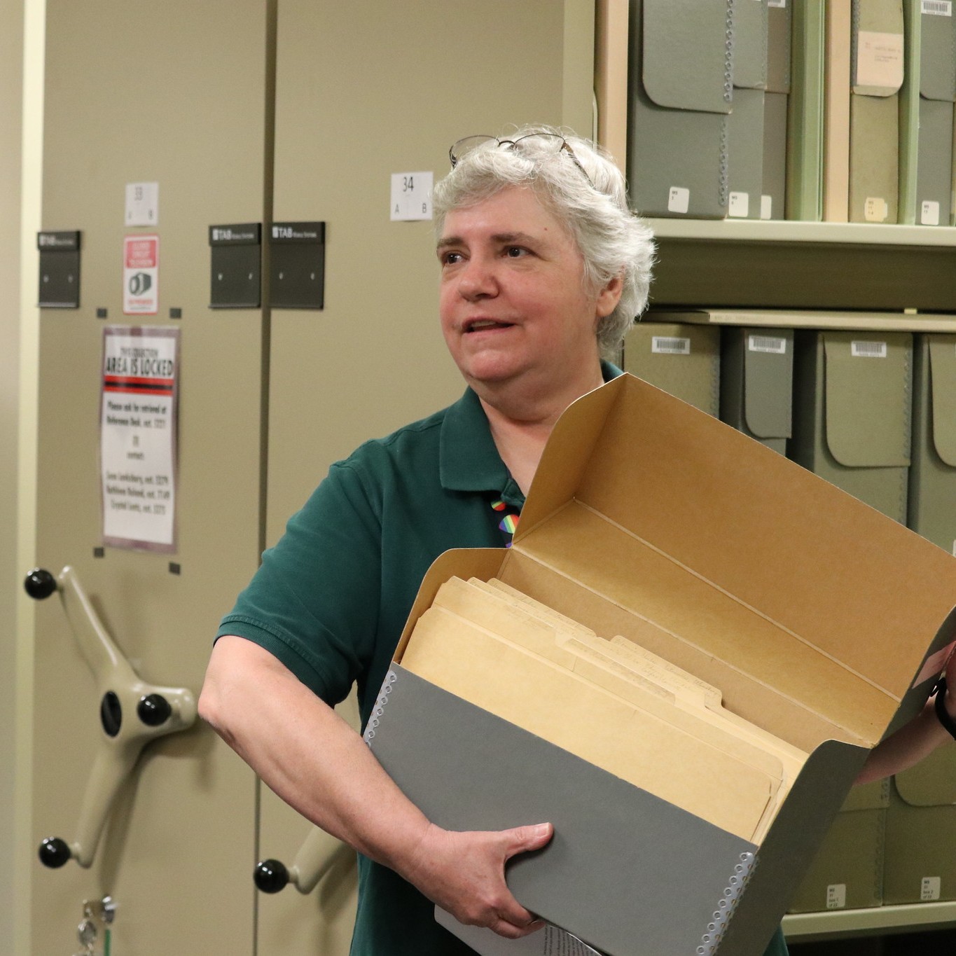 Woman holding file folder in front of library stacks