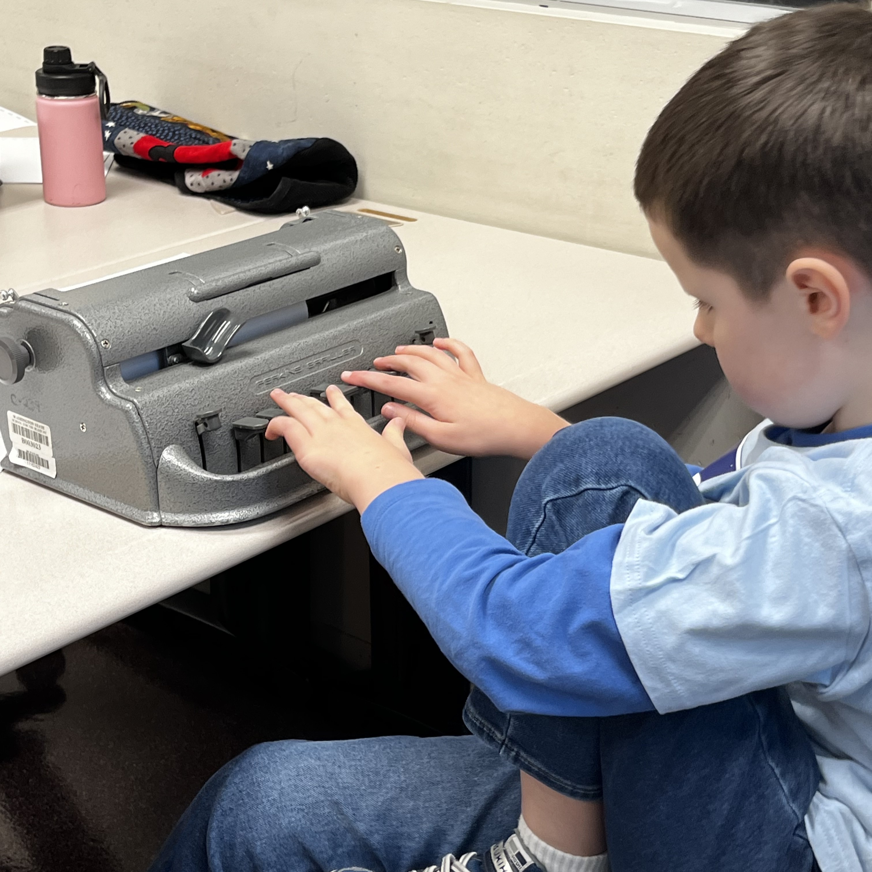 A youth patron utilizing a brailler