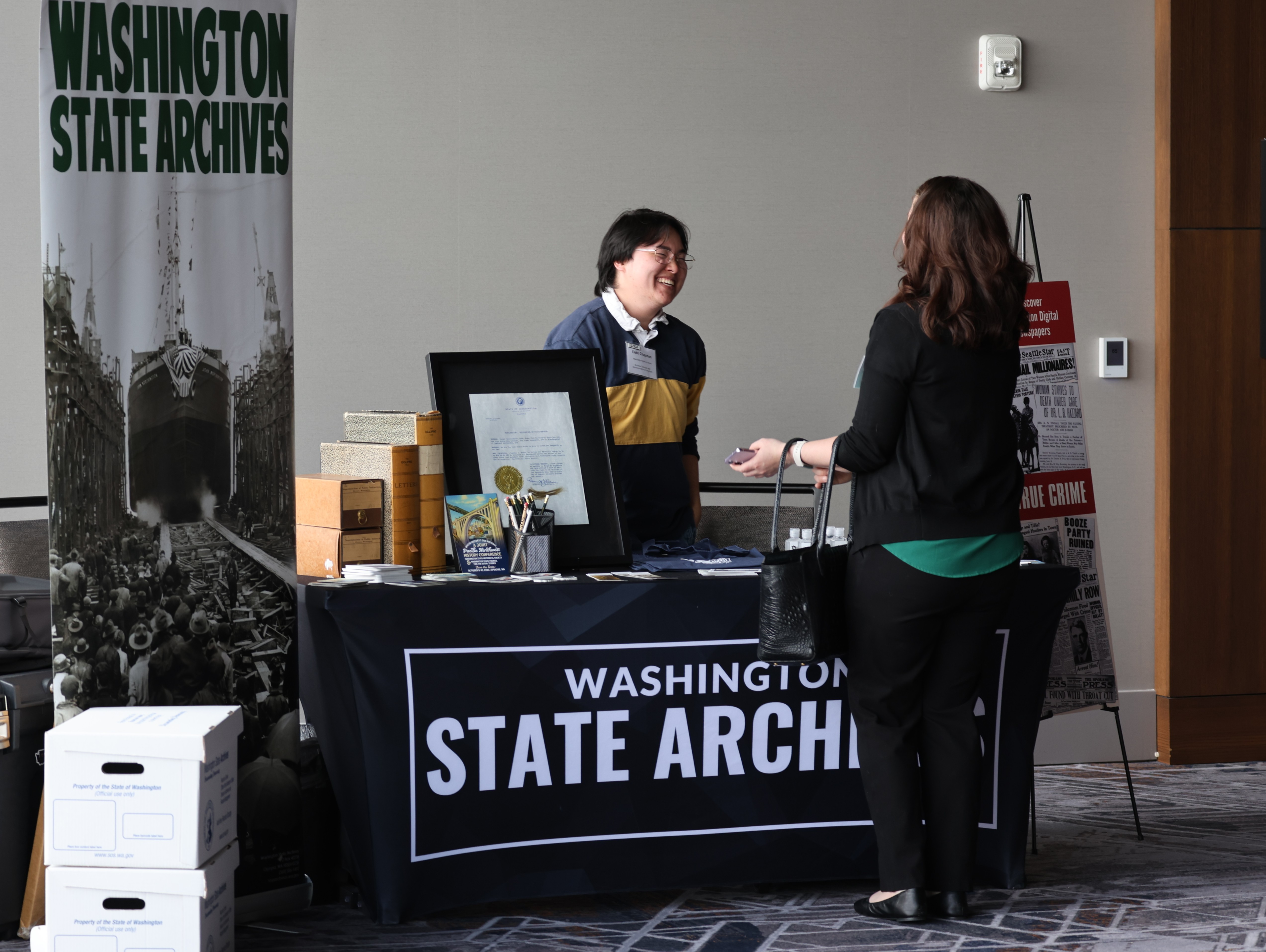 A State Archives employee tabling at an event engaged in conversation with an attendee.